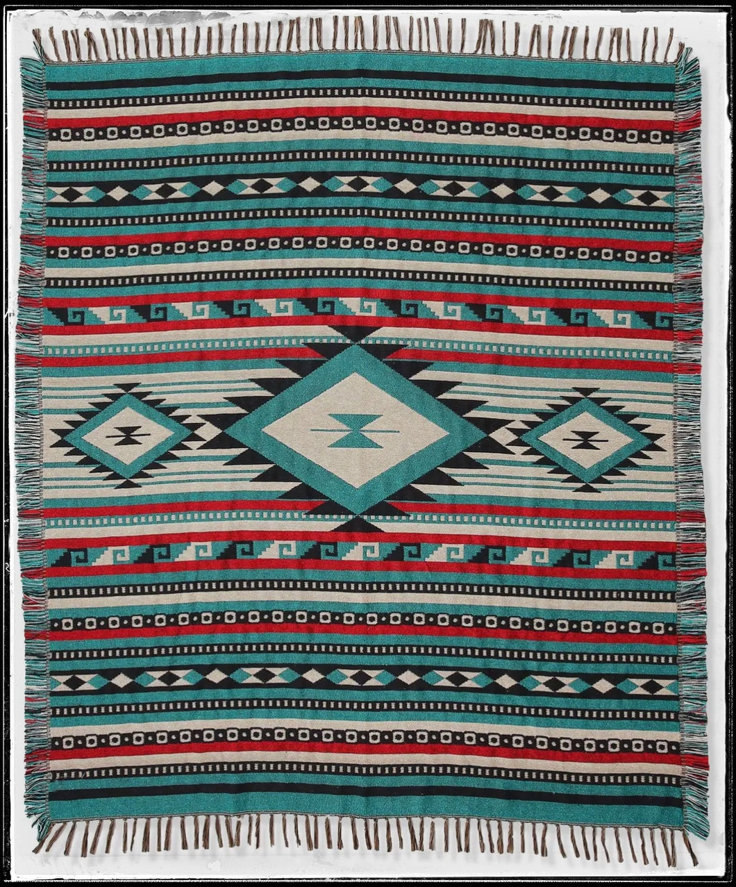 Cotton throw blanket with fringed edges. Bold, aztec print in teals, red, and black. 